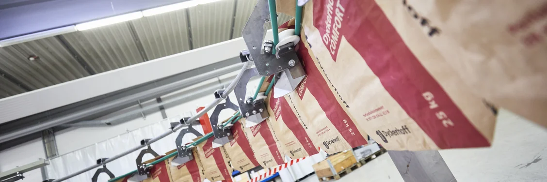 HAVER & BOECKER PATHFINDER automatisiertes Sackhandhabungssystem, das leere Säcke von RADIMAT zu ROTO-PACKER in einer vollautomatischen Verpackungslinie transportiert.